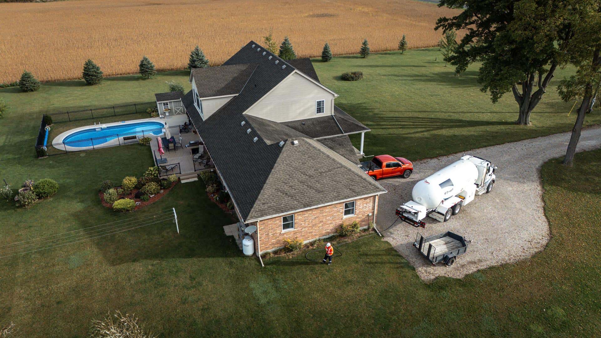 Modern home receiving an automatic propane delivery from a McDougall Energy truck parked in the driveway.