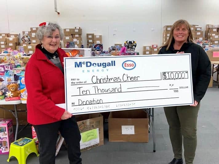 $10,000 donation check for Christmas Cheer by McDougall Energy at charity event.