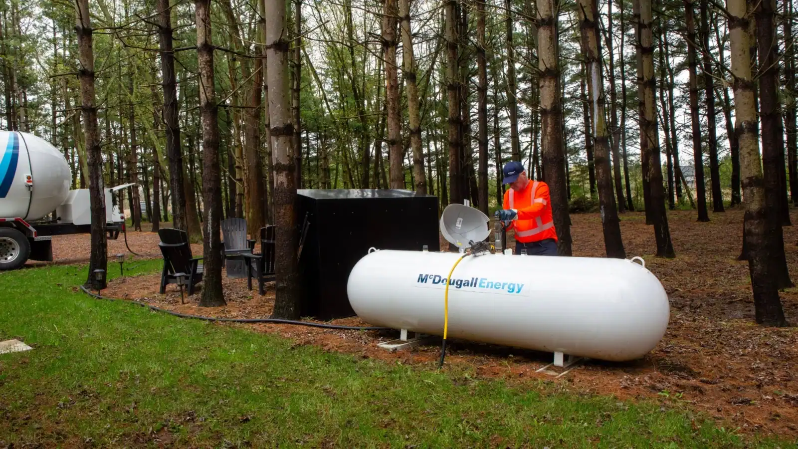 Propane tank setup outdoors in wooded area for energy needs.