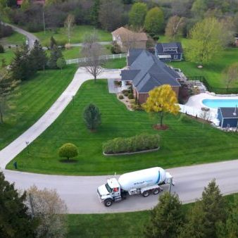 McDougall Energy propane delivery truck on residential driveway, home with pool, lush landscaping.