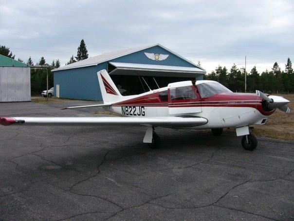 Small airplane parked near a hangar at an airport.