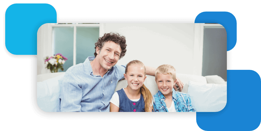 father sitting with kids on a couch smiling at camera